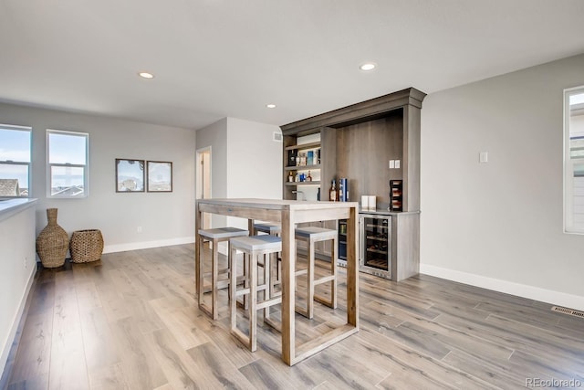 interior space featuring bar, light hardwood / wood-style flooring, and beverage cooler