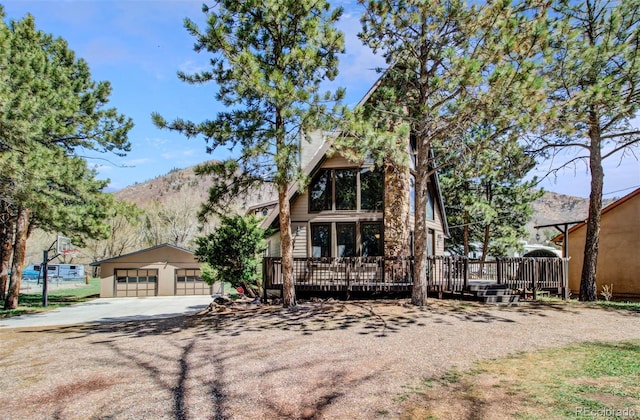 a-frame style home with a detached garage, an outdoor structure, and a deck with mountain view
