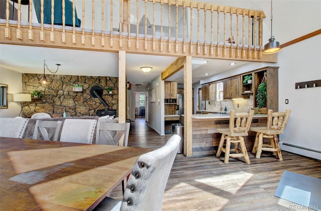 dining space with a wood stove, wood finished floors, and a high ceiling