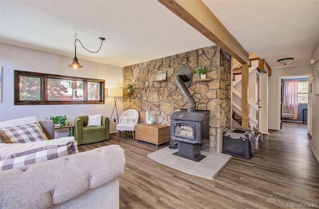 living area with wood finished floors, a wood stove, baseboards, and beamed ceiling