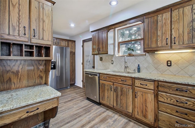 kitchen with stainless steel appliances, a sink, backsplash, light wood-style floors, and recessed lighting