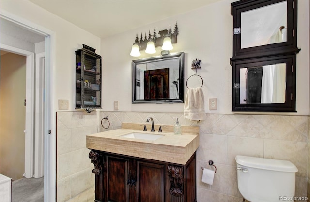 bathroom featuring tile walls, toilet, vanity, and wainscoting