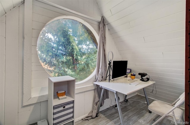 home office featuring vaulted ceiling, light wood-style floors, and wooden walls