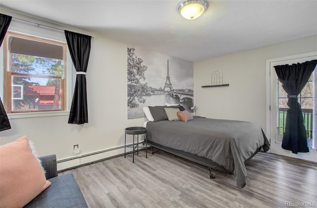 bedroom with a baseboard radiator, wood finished floors, and access to exterior