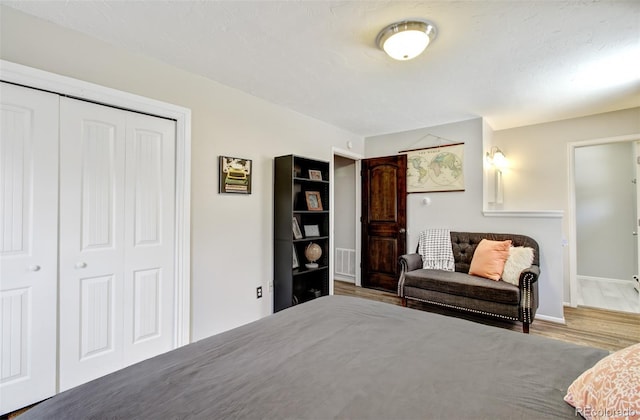 bedroom with wood finished floors, a closet, and baseboards