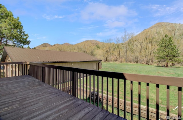 wooden deck with a mountain view and a lawn