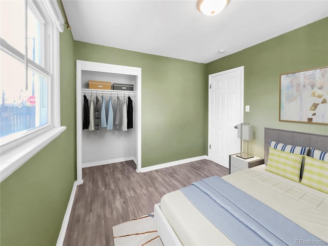 bedroom featuring dark wood-style flooring, baseboards, and a closet
