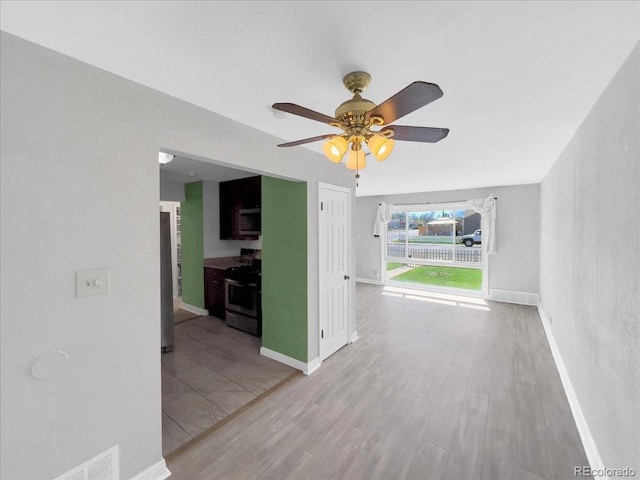 interior space with light wood-style floors, baseboards, and a ceiling fan