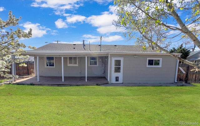 rear view of property featuring fence and a yard