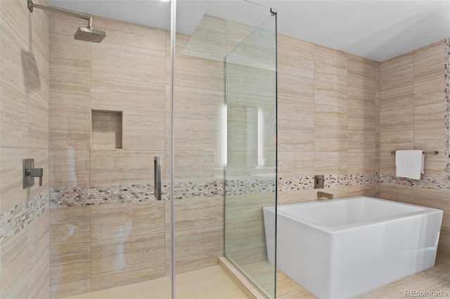 bathroom featuring tile patterned floors, tile walls, and independent shower and bath