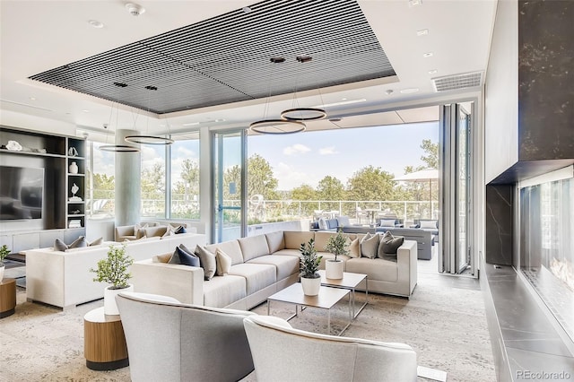 living room with a raised ceiling and floor to ceiling windows