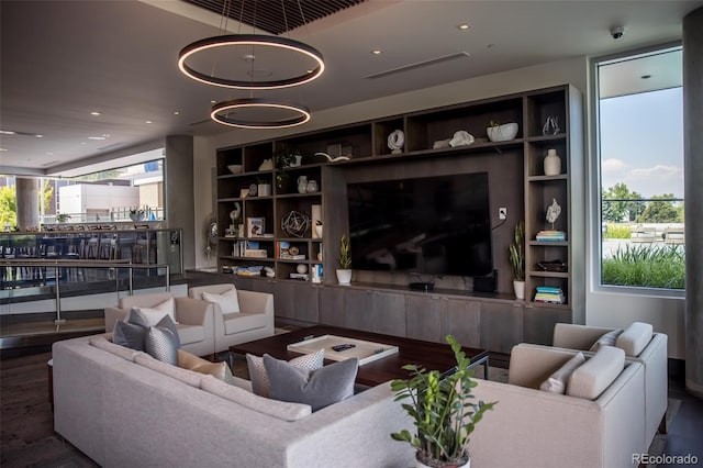 living room with built in features, wood-type flooring, and a notable chandelier