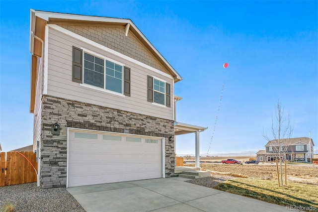 exterior space featuring a garage, fence, stone siding, and driveway