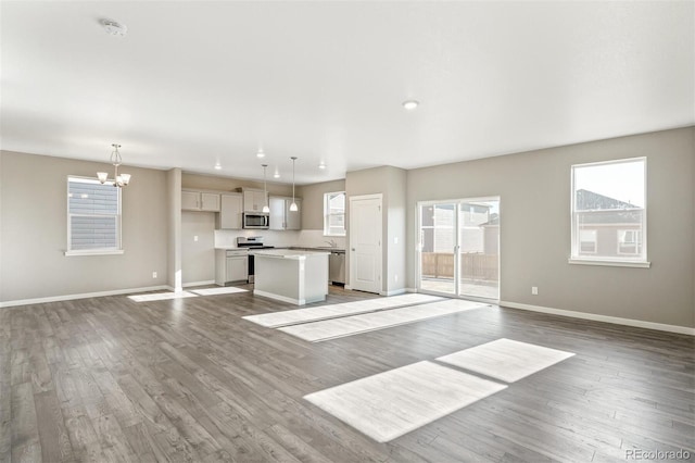 unfurnished living room with recessed lighting, a chandelier, baseboards, and dark wood-style floors