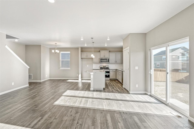 kitchen featuring baseboards, open floor plan, light wood-type flooring, light countertops, and stainless steel appliances