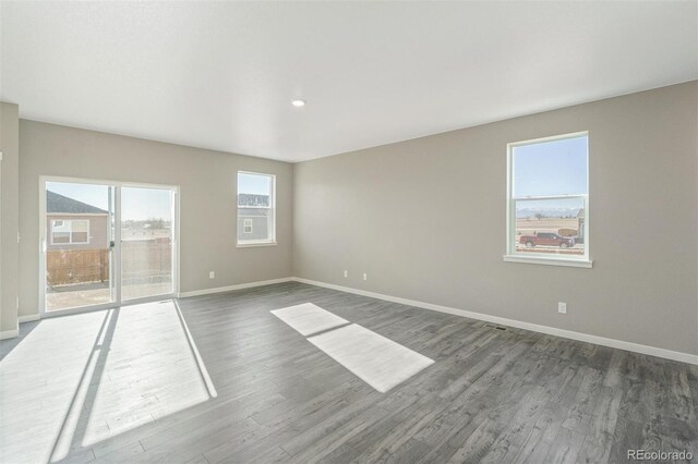 spare room with baseboards and dark wood finished floors