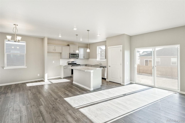 kitchen featuring appliances with stainless steel finishes, a center island, dark wood-type flooring, and a sink