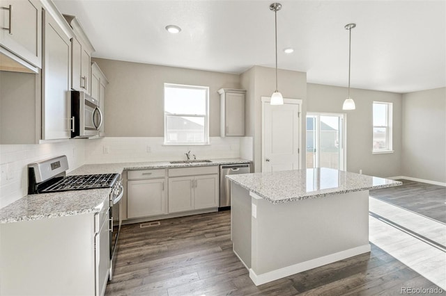 kitchen with a sink, tasteful backsplash, dark wood finished floors, stainless steel appliances, and a healthy amount of sunlight