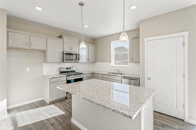 kitchen with a sink, stainless steel appliances, light wood-type flooring, backsplash, and a center island