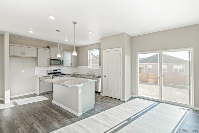 kitchen with a kitchen island, stainless steel appliances, wood finished floors, and a sink