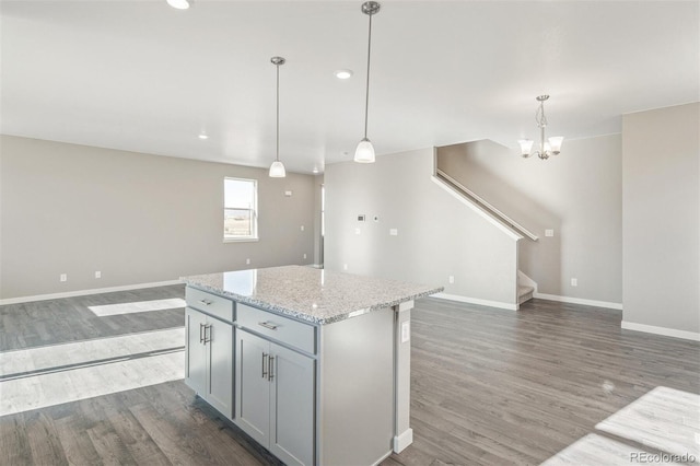 kitchen featuring wood finished floors, baseboards, a kitchen island, gray cabinetry, and open floor plan