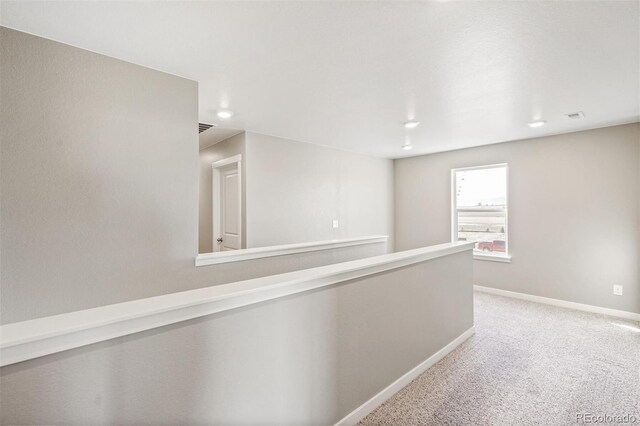 hallway with an upstairs landing, carpet flooring, visible vents, and baseboards