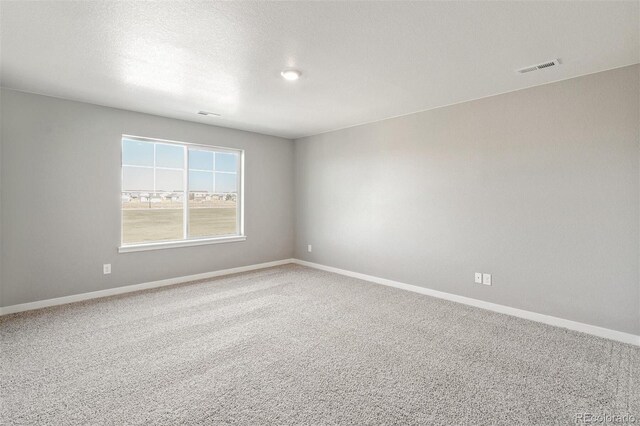 carpeted spare room with visible vents, baseboards, and a textured ceiling