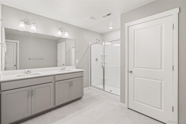 full bathroom with a shower stall, double vanity, visible vents, and a sink