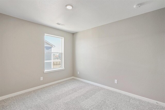 carpeted spare room with visible vents, a textured ceiling, and baseboards