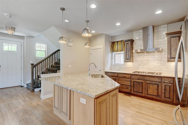 5080 Uinta St, Denver, CO 80238 - kitchen featuring wall chimney exhaust hood, light wood-style flooring, tasteful backsplash, brown cabinetry, and recessed lighting