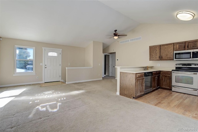 kitchen with light carpet, stainless steel appliances, vaulted ceiling, and ceiling fan