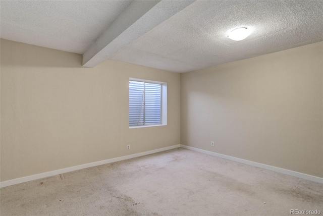 carpeted empty room with beamed ceiling and a textured ceiling