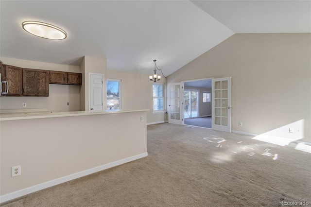 kitchen with pendant lighting, an inviting chandelier, french doors, vaulted ceiling, and light colored carpet