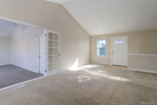 carpeted entrance foyer featuring french doors and vaulted ceiling