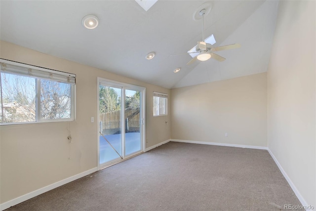 carpeted spare room featuring ceiling fan and lofted ceiling with skylight