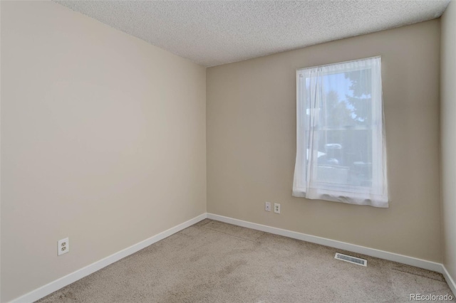 carpeted empty room featuring a textured ceiling