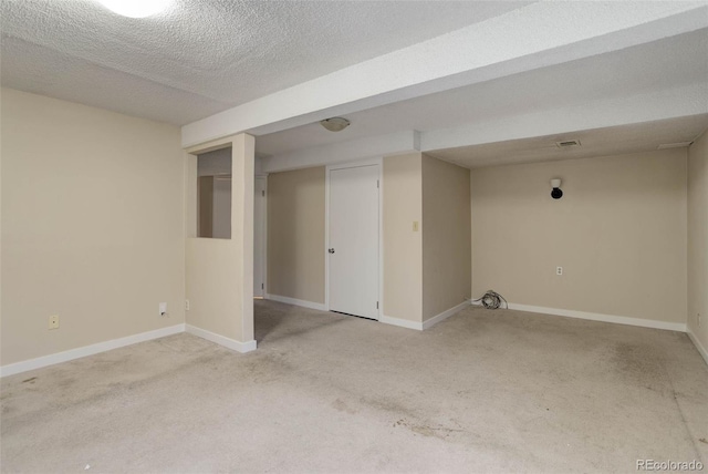 basement featuring light carpet and a textured ceiling