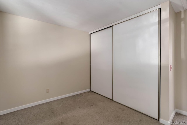 unfurnished bedroom with light carpet and a closet