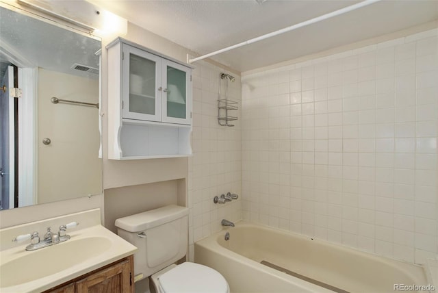 full bathroom with a textured ceiling, vanity, toilet, and tiled shower / bath