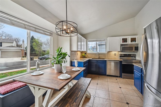 646 S Joplin St, Aurora, CO 80017 - kitchen featuring stainless steel appliances, blue cabinets, lofted ceiling, decorative backsplash, and a chandelier