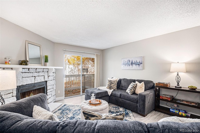 living room featuring a stone fireplace, light hardwood / wood-style floors, and a textured ceiling