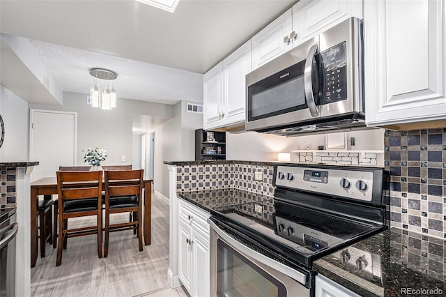 kitchen with white cabinets, pendant lighting, stainless steel appliances, and tasteful backsplash