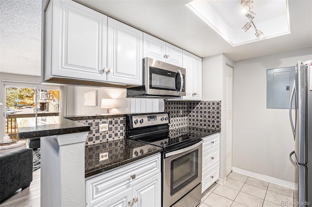 kitchen featuring a textured ceiling, appliances with stainless steel finishes, tasteful backsplash, light tile patterned flooring, and white cabinetry