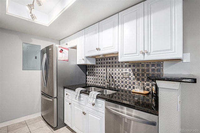 kitchen with appliances with stainless steel finishes, white cabinetry, dark stone counters, and sink