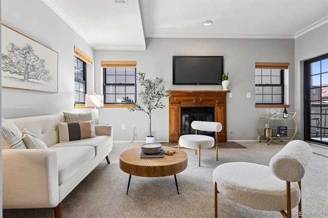 carpeted living room featuring a glass covered fireplace, baseboards, and ornamental molding