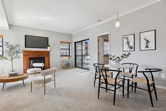 carpeted dining space featuring baseboards, a glass covered fireplace, and crown molding