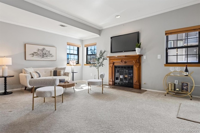 carpeted living area with a glass covered fireplace, visible vents, baseboards, and ornamental molding