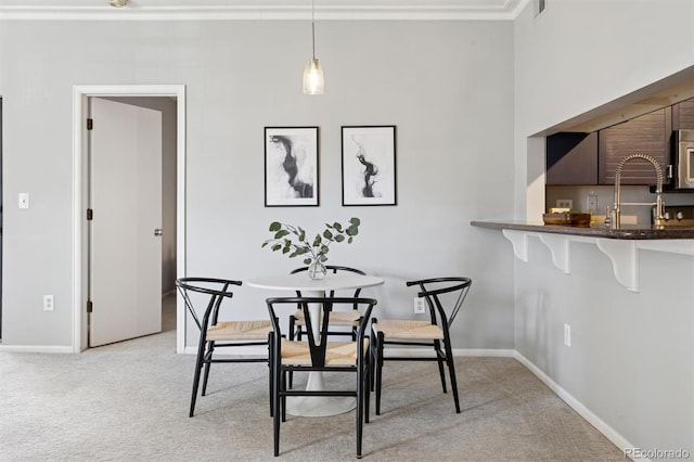 dining room featuring baseboards, light carpet, and ornamental molding