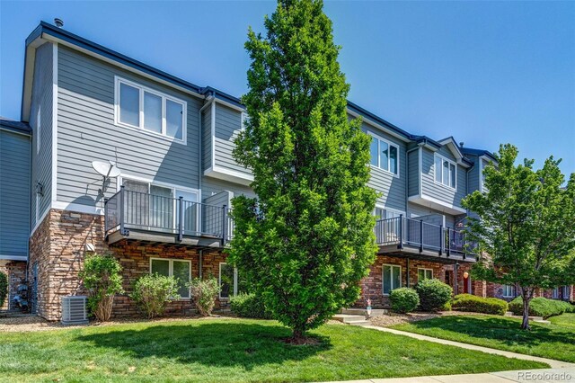2763 W Riverwalk Cir Unit B, Littleton, CO 80123 - rear view of house featuring a lawn, cooling unit, and stone siding