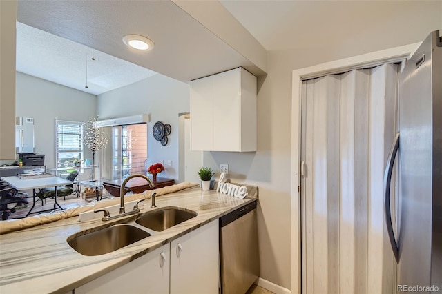 kitchen with white cabinetry, appliances with stainless steel finishes, sink, and light stone countertops